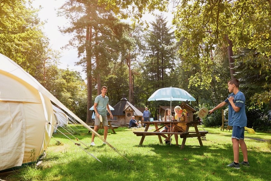 Vader en zoon aan het tennissen voor een Bell tent op de Veluwe