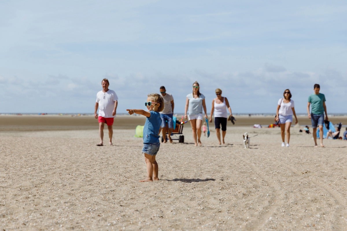 Groot gezin wandelt op het strand van de Noordzee